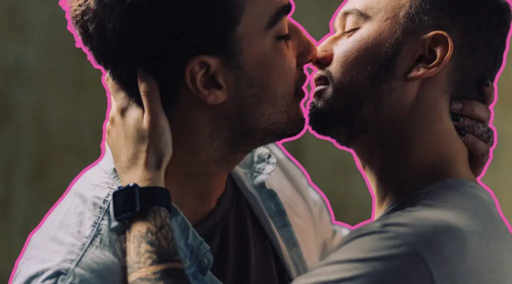 Pareja de hombres se besa mientras se abraza.