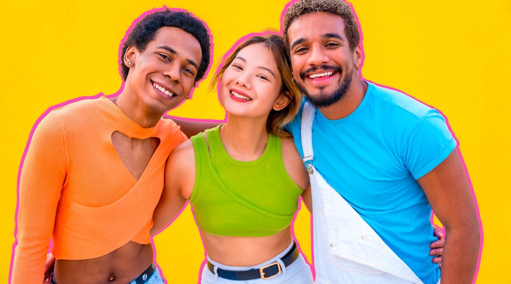 Tres jóvenes sonríen juntos frente a un fondo amarillo.