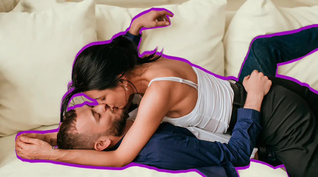Pareja se abraza y se besa mientras está recostada en la cama.