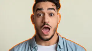 Hombre con expresión de sorpresa sobre fondo claro.