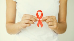 Persona sostiene un lazo rojo de concientización sobre el VIH.