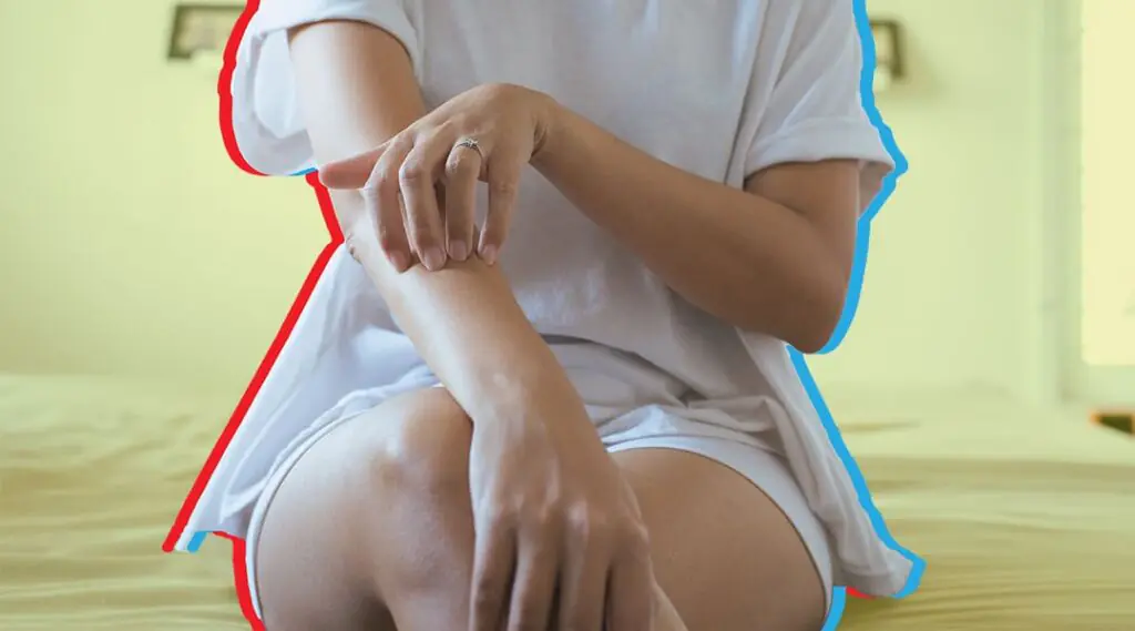 Persona se rasca el brazo mientras está sentada.