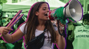 Mujer habla por un megáfono durante una movilización en espacio público.