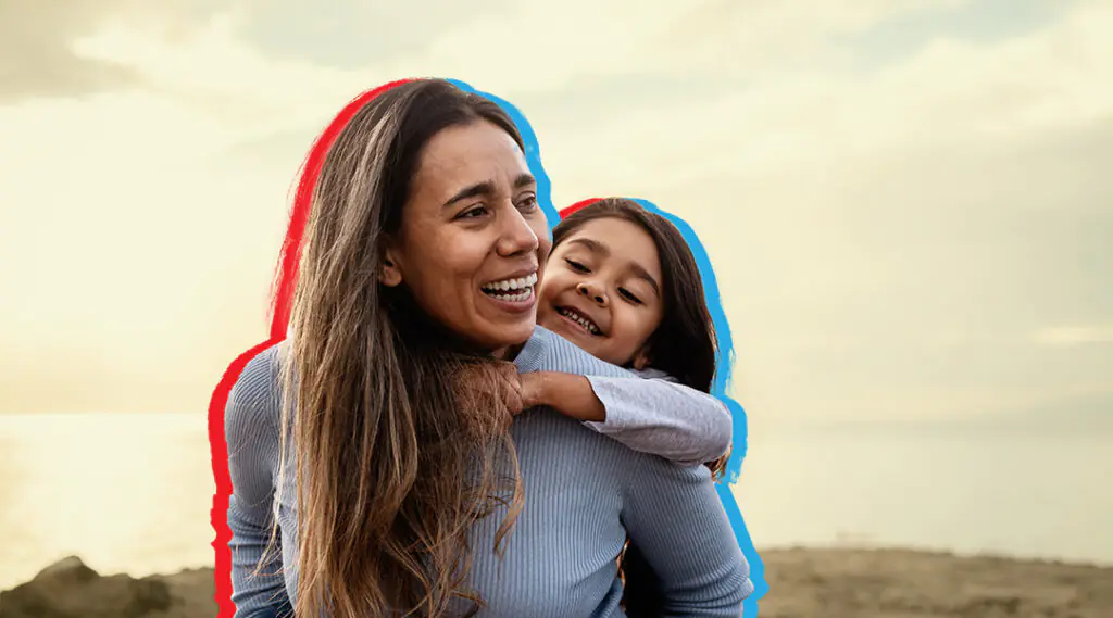 Madre e hija se abrazan y sonríen al aire libre.