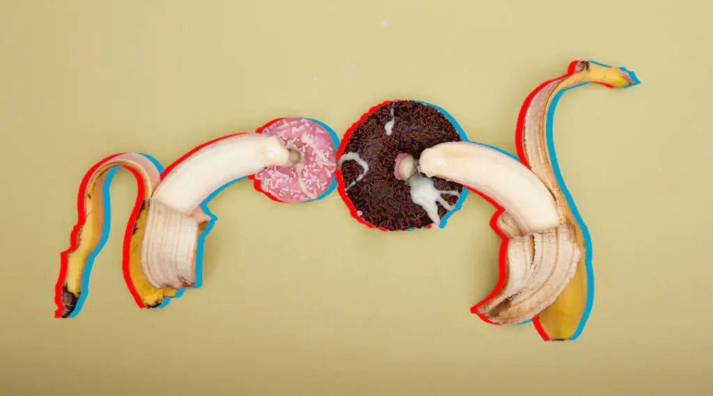 Dos bananas enfrentadas con una galleta en el centro sobre fondo claro.