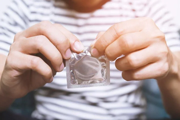 Persona abre un preservativo como parte de prácticas de prevención sexual.