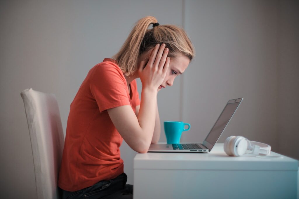 Mujer se toma la cabeza mientras trabaja frente a una computadora portátil