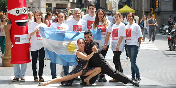 Integrantes de AHF Argentina celebran el Día Internacional del Preservativo con bandera argentina y preservativo inflable en actividad pública.