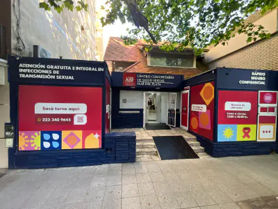 Entrada del centro comunitario de AHF Argentina con carteles sobre atención gratuita e integral en infecciones de transmisión sexual.